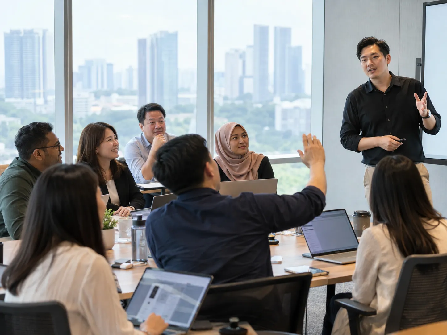 A training session in progress: a trainer at the whiteboard, a participant with a hand raised